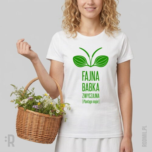 Modelka w białej koszulce zielarskiej z humorystycznym nadrukiem projektu graficznego babki zwyczajnej (Plantago major) z napisem pod nim FAJNA BABKA ZWYCZAJNA, trzymająca na przedramieniu wiklinowy koszyk ze świeżymi ziołami.