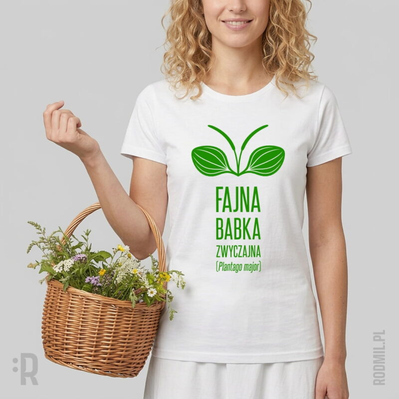 Modelka w białej koszulce zielarskiej z humorystycznym nadrukiem projektu graficznego babki zwyczajnej (Plantago major) z napisem pod nim FAJNA BABKA ZWYCZAJNA, trzymająca na przedramieniu wiklinowy koszyk ze świeżymi ziołami.